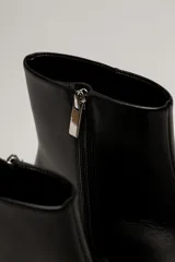 Bota corta de cuero negro con punta fina y taco bajo rectangular.