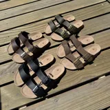 Sandalias de cuero sintético color verde militar, con plantilla marrón y hebillas metálicas doradas.