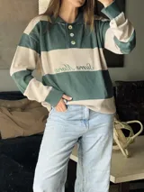 Sweater de hilo de algodón a rayas horizontales rosas y grises, con cuello polo, botones de guampa y bordado de Sierra Mora a tono.