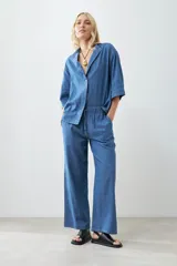 Camisa de jean celeste de corte recto, con cuello mao, mangas cortas y cierre frontal con botones.