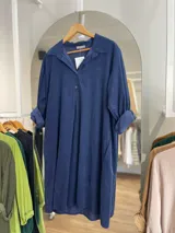 Vestido camisero verde militar de pana con cuello camisero, abotonado hasta la mitad del frente y mangas largas con puños abotonados.