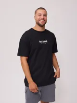 Remera negra de algodón con estampado en la espalda que incluye un sol estilizado, texto con la marca "Rusty" y la frase "Golden Sun - Endless Waves".