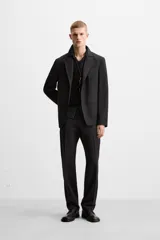Blazer negro de lana con cuello de solapa de muesca, corte recto, manga larga con puños abotonados, bolsillos de vivo en el pecho y de solapa en la cadera, abertura en la parte posterior y cierre frontal con botones. Colección Origins.