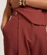 Pantalón de sastrería color terracota, modelo wide leg, con cintura con trabillas y detalle de hebilla lateral. Presenta cierre tradicional y bolsillos tipo cuchillo.