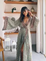 Kimono largo de seda con estampado floral en tonos verde, marrón y beige. Tiene mangas amplias y corte cruzado con lazo ajustable en la cintura.