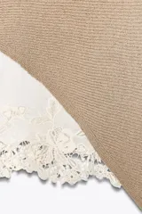 Top color beige de tejido de punto con mangas 3/4 y bajo asimétrico. Detalle de tejido combinado doble capa con encaje blanco en el ruedo.