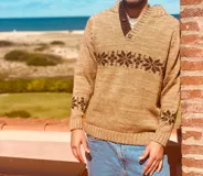 Sweater tostado de lana con cuello en V y diseño de copos de nieve en marrón.