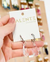 Par de aros colgantes con aro de acero plateado y dije transparente en forma de lágrima.