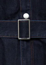 Mono largo de denim azul oscuro, con cuello camisero, mangas largas con puños abotonados, trabillas, cinturón con hebilla metálica, cierre frontal con botones a presión y cuatro bolsillos.