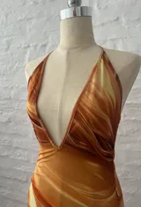 Vestido corto con estampado abstracto en tonos naranja, blanco y marrón. Diseño con escote halter y falda con volados.