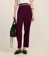Pantalón de vestir azul marino, de corte zanahoria, con cinturón fino negro con hebilla dorada.