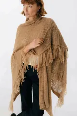 Ruana de punto color beige con cuello alto y flecos.