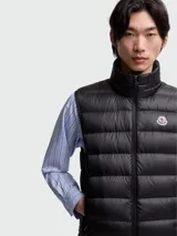 Chaleco puffer negro con diseño acolchado de costuras horizontales, cuello alto y cierre frontal de cremallera. Incluye el parche del logo de Moncler en el pecho.