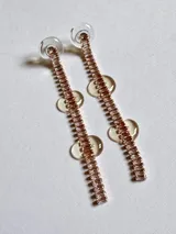 Par de aros colgantes con forma de barra vertical, con strass color rosa y apliques circulares de acrílico transparente.