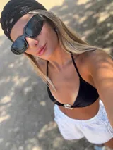 Conjunto de bikini negro con corpiño triangular con argolla metálica y bombacha colaless con tiras para atar y argollas en los costados.