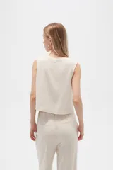 Musculosa color crema de viscosa, sin mangas, corte holgado, con cuello a la base y cierre frontal con botones.