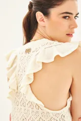 Musculosa tejida en hilo de algodón con punto desagujado, de calce al cuerpo y volados en las sisas.