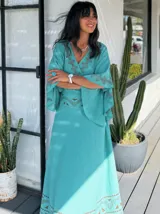 Pollera larga color celeste con estampado de guardas geométricas en color marrón en la cintura y el ruedo. Corte amplio y fluido.