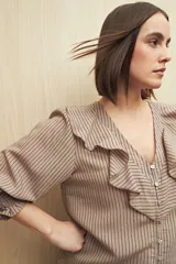 Camisa blanca a rayas verticales, con escote en V, mangas 3/4 con puños elastizados y volados.