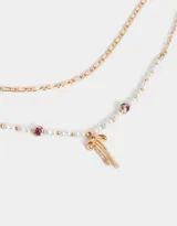 Collar corto multicadena dorada, con una cadena de eslabones y otra de perlas sintéticas con cuentas florales y dije de moño metálico.
