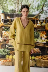 Blusa color crudo de lino con cuello en V y ribete marrón.