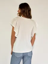 Remera blanca de algodón con escote en V y mangas cortas con volados y detalle de puntilla.