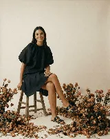 Vestido corto negro de lino, con cuello redondo, mangas cortas abuchonadas y corte evasé con volado en el ruedo.