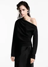 Blusa negra asimétrica con un hombro descubierto, detalle fruncido, tejido con lentejuelas y cierre lateral con cremallera.