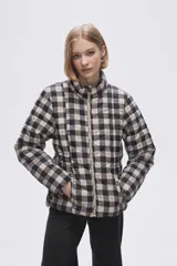 Campera puffer estampada a cuadros en blanco y negro con pequeños corazones rosados, cierre frontal con cremallera y bolsillos laterales.