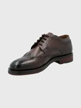 Zapato de vestir marrón oscuro con cordones, estilo Oxford, con detalles de perforaciones y costuras en cuero.