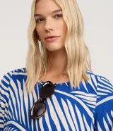 Vestido corto estilo camiseta, con escote redondo y mangas cortas. Presenta un estampado de follaje en blanco y azul vibrante.