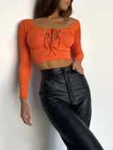 Top corto color naranja, de mangas largas y escote con lazo.