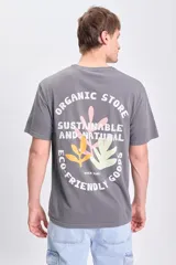 Remera gris oscuro de manga corta, corte oversize y estampa en la espalda con texto y diseño de hojas.