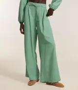 Pantalón wide leg color verde agua, de tiro alto y corte sastrero, con cintura elástica en la espalda, cinturón incorporado para lazo, pliegues delanteros y bolsillos laterales.