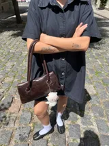 Vestido camisero corto negro de denim, con cuello clásico, cierre frontal con botones, mangas cortas, bolsillos cuadrados en el pecho y corte recto.