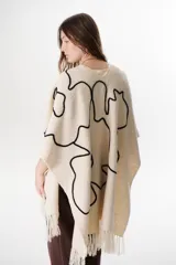 Ruana color marrón con flecos y bordados en el contorno.