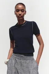 Top de punto color crema, de cuello redondo y manga corta con detalle de vivos a contraste en cuello y hombros.