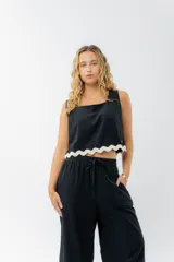 Top de lino color crudo, con escote cuadrado y detalle de guarda ondulada negra en el ruedo.