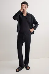 Pantalón negro de corte recto, confeccionado en mezcla de lino y algodón. Presenta cintura elástica con cordón ajustable, bolsillos laterales y bolsillo trasero insertado.