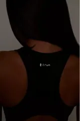 Top deportivo negro con diseño nadador, entrada para almohadillas removibles, bolsillo trasero y detalle reflectivo.