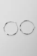 Par de aros tipo argolla plateados con superficie facetada.
