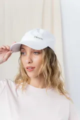 Gorra de béisbol color amarillo pastel, con visera curva y logo de Peach bordado en el frente. Ajustable en la parte trasera.