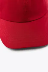 Gorra roja con visera confeccionada en hilatura de algodón 100% y ajuste en la parte posterior.