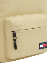 Mochila Tommy Jeans color beige con detalles en negro. Tiene un bolsillo frontal con cierre, asa superior, correas acolchadas ajustables y logo de la marca en el frente.