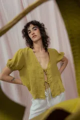 Blusa color verde oliva de lino, con escote en V y mangas cortas abullonadas. Se ata en el frente con dos pares de lazos.