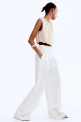 Top cropped color beige, sin mangas, de punto suave y silueta abullonada con efecto drapeado.