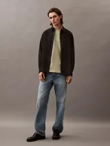 Remera color verde oliva de corte holgado, con cuello redondo, mangas cortas y bolsillo en el pecho con logo bordado.