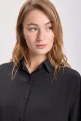 Camisa negra de manga larga con cuello clásico y cierre frontal con botones.