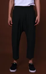 Pantalón negro de corte holgado con tiro bajo, largo a la pantorrilla y cintura elástica.