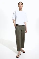 Pantalón cigarette tobillero color verde oliva, con cintura estándar, cierre y pretina prolongada con corchete oculto. Piernas ajustadas con abertura corta en los bajos, bolsillos al bies y bolsillo de atrás decorativo. Pliegues adelante y atrás.